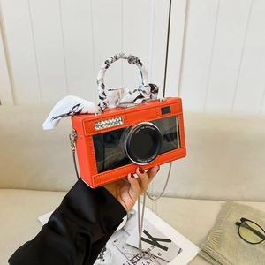 Unique orange camera-shaped crossbody bag with rhinestone lens and silk scarf handle