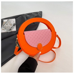 Macro detail of a round orange handbag with woven pink lid and elegant metallic buckle