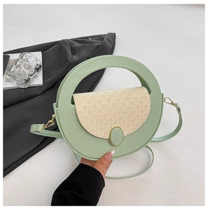 Close-up of light green crossbody bag featuring straw woven texture and gold metal buckle