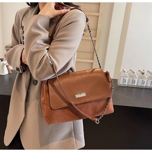 Detail of caramel leather and suede handbag with silver chain strap on a model