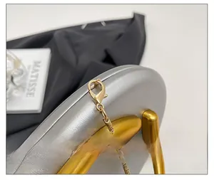 Detailed close-up of premium gold lobster clasp and snake chain on a silver evening bag