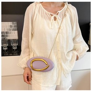 Detail of lavender oval leather shoulder bag with bold gold metal ring and chain strap