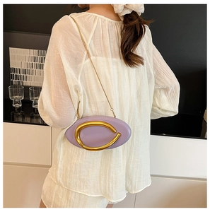 Detail view of purple oval chain bag with gold metal ring on a minimalist backdrop