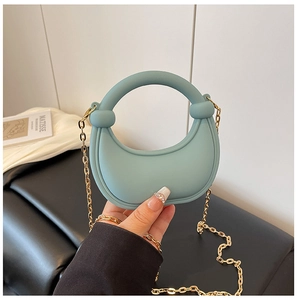 Detail of light blue crescent acrylic bag with gold chain and round handle