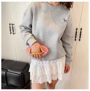 Close-up of grey sweatshirt with red embroidery and white layered lace skirt
