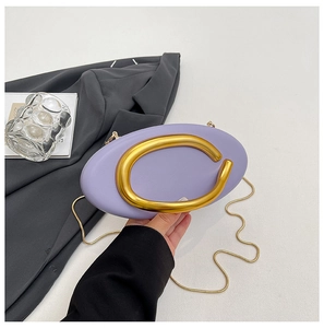 Detail of lavender oval bag with gold ring handle and chain strap on grey blazer