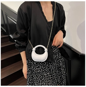 Chic white crescent acrylic handbag with gold chain strap shown on model's shoulder