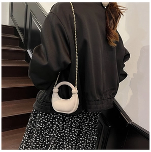 Creamy white crescent handbag with gold chain strap shown as a crossbody accessory