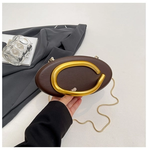 Detail view of dark brown leather oval clutch with signature gold metal C-shaped handle