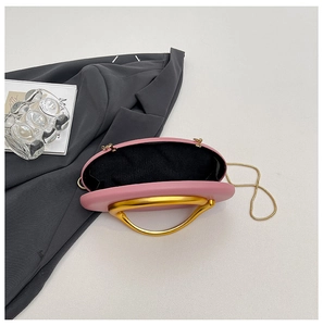 Detailed interior of a pink leather evening bag with golden handle and chain strap