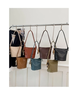 Row of woven bucket bags in seven colors with beaded charms on a minimalist rack