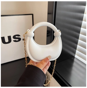Detail of white acrylic crescent handbag with circular handle and gold chain strap
