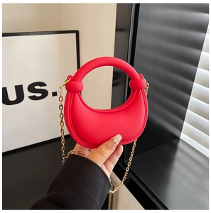 Detail of red crescent-shaped acrylic clutch bag with golden chain and round handle