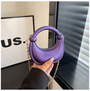 Detail view of purple crescent acrylic evening bag with gold chain and round handle