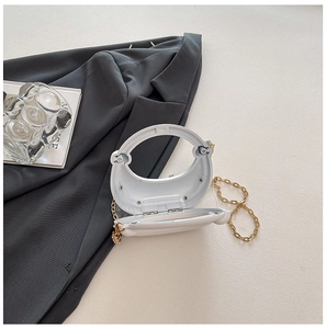 Detail of white acrylic crescent bag interior showing the hinge and golden chain strap