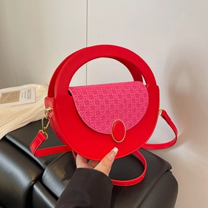 Red and pink minimalist circular crossbody bag with round handle and metal accents
