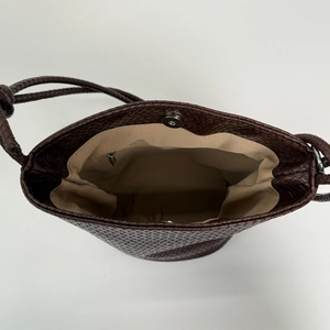 Interior view of woven bucket bag with magnetic snap and beige fabric lining