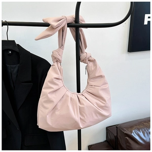 Close-up of pink ruched shoulder bag with a stylish bow strap and silver zipper closure