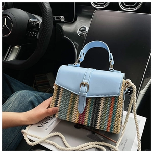 Detail einer bunt gestreiften Strohhandtasche mit hellblauem Lederdeckel für den Urlaub