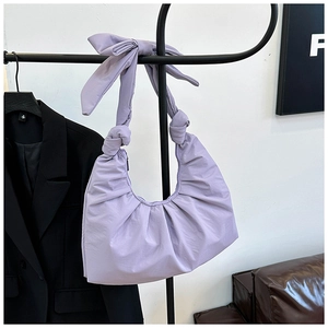 Detail of purple pleated crescent bag featuring stylish bow knot shoulder strap design