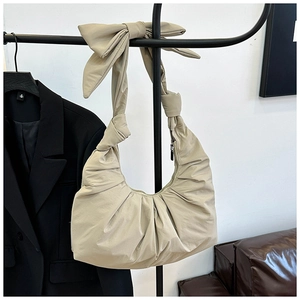 Detail of beige pleated cloud bag with soft ruched design and decorative bow strap