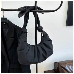 Detail of black pleated crescent bag featuring oversized bow strap and silver zipper
