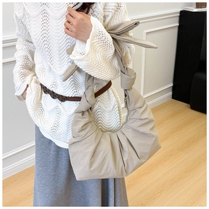 Detailed close-up of bow knot strap on pleated oatmeal crescent shoulder bag for women