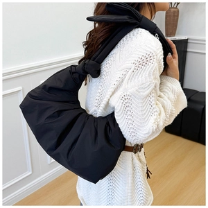 Detail of a black pleated underarm bag in soft nylon fabric with stylish knot shoulder strap