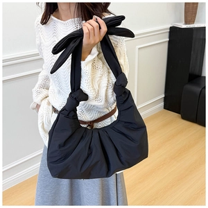 Detailed close-up of a black pleated shoulder bag featuring a stylish large bow decoration
