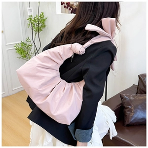 Close-up of pink puffy crescent bag featuring a large decorative bow and soft pleats