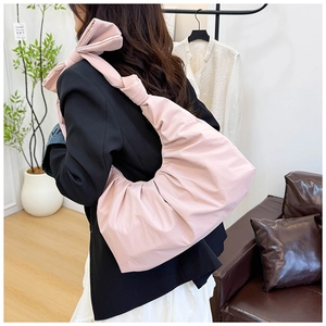 Detail view of pink pleated shoulder bag with knotted strap design and stylish ribbon