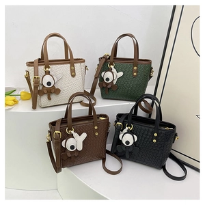 Détail de sacs à main tressés en quatre couleurs avec breloques singe et poignées