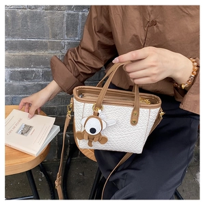 Détail du sac seau blanc tressé avec poignées marron et charm de singe mignon
