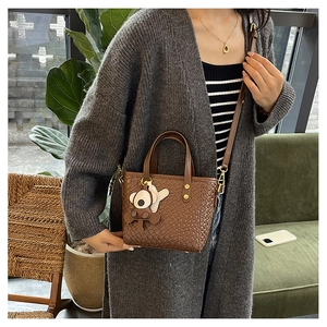 Détail d'un sac seau tissé marron avec pendentif koala et boucles métalliques dorées