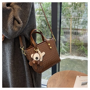 Détail du sac cabas tissé marron foncé avec bandoulière amovible et breloque d'ours