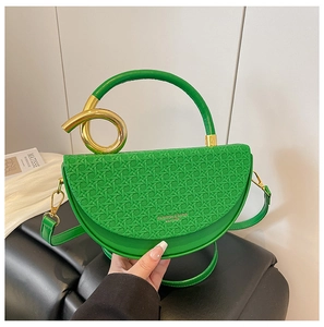 Close-up of green saddle bag with woven texture and artistic gold metal handle decor