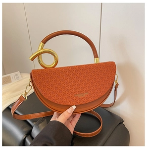 Detail of caramel leather saddle bag with woven texture and gold circular metal handle