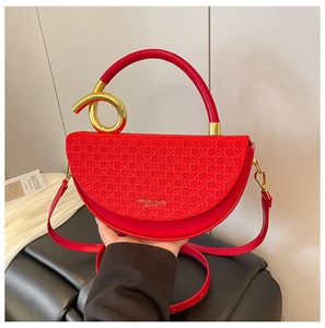 Detail of red saddle bag with woven texture lid and round handle with gold ring accent