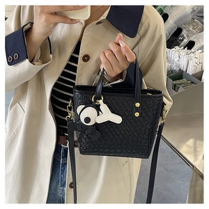 Détail du sac seau noir en cuir tressé avec clous dorés et pendentif ours stylé