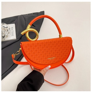 Detailed close-up of orange woven saddle bag with gold ring buckle and leather logo strap