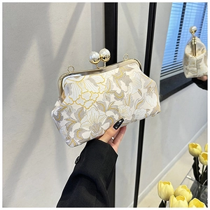 Détail de broderies florales et fermoir perle sur une pochette de soirée vintage