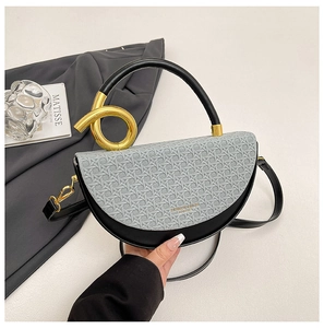 Detail view of saddle bag with grey woven texture, gold lettering, and unique metal ring hardware
