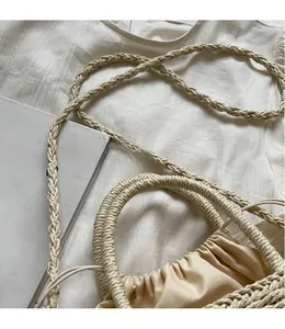 Close-up of woven straw shoulder bag with long braided strap and drawstring closure