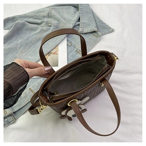 Détail du sac seau marron tressé avec poche intérieure, fermeture éclair et pendentif