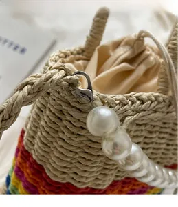 Detailed shot of rainbow woven bag featuring elegant pearl pendant and metal clasp