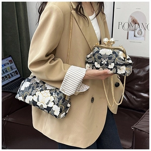 Détail d'un sac à main brodé à fleurs avec fermoir perle dorée et bandoulière chaîne