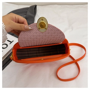 Macro shot of orange saddle bag with pink woven texture flap and golden round lock