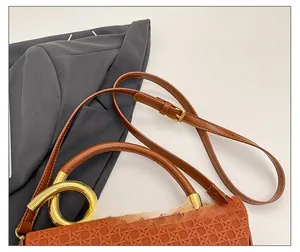 Detail view of woven brown leather texture and golden metal buckle on adjustable strap