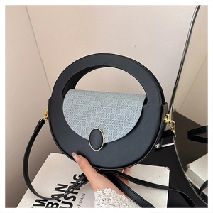 Detail of a round leather shoulder bag with grey woven flap and gold hardware accents