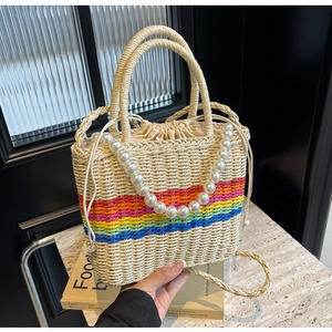 Detailed straw bucket bag featuring rainbow stripes, pearl handle, and drawstring closure